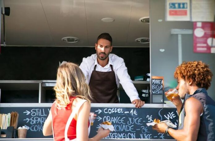 Two business partners standing in front of their food truck